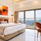 Premium hotel room featuring a compact kitchenette, work table, wall-mounted TV, and elegant modern décor.
