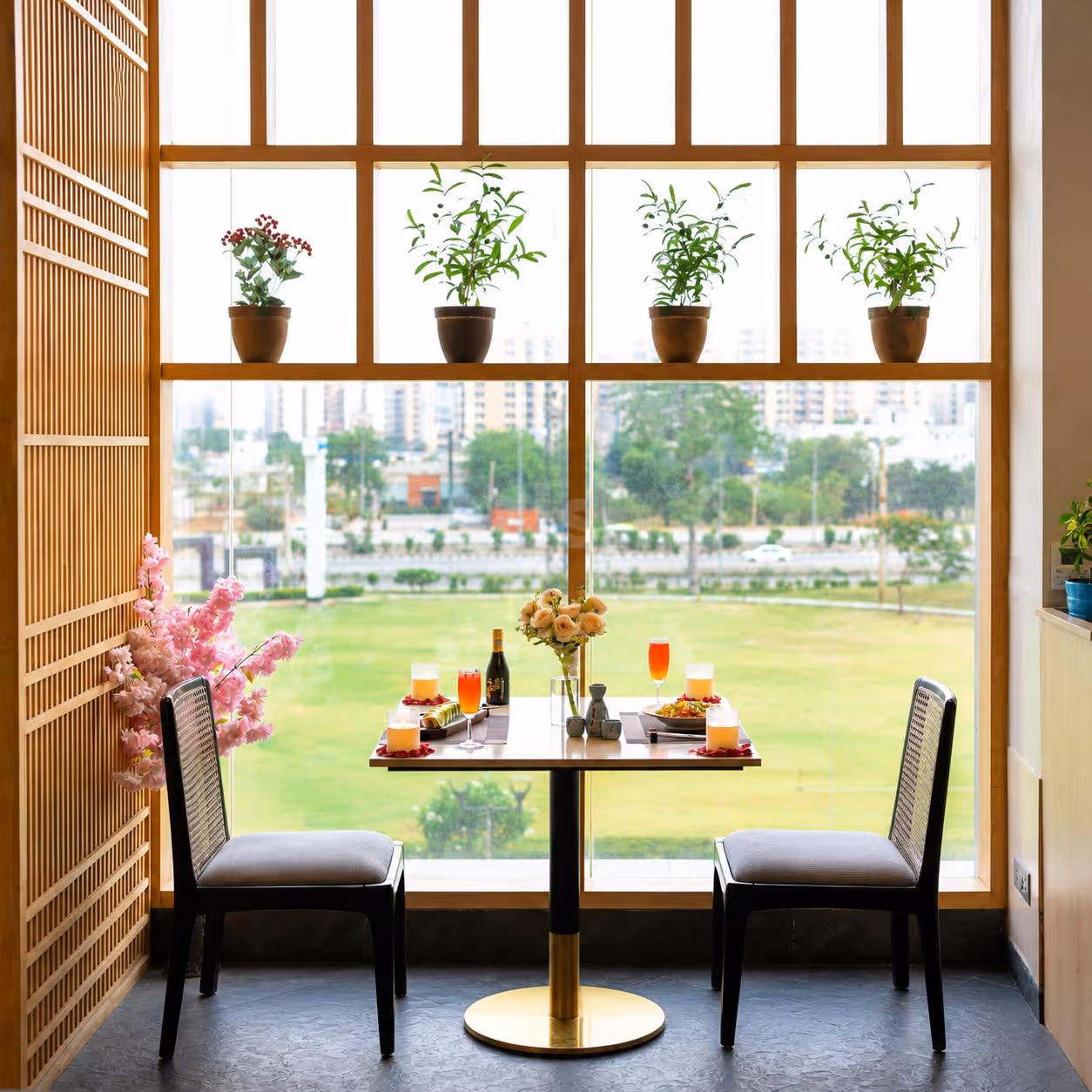 Elegant window-side dining table featuring sushi platter, refreshing mocktails, candlelight décor, and a scenic outdoor view.