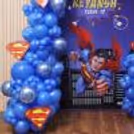 Superhero theme birthday decoration including balloon clusters, themed paper cutouts, personalised flex and matching balloon pillar.