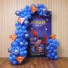 Superhero birthday balloon arch with personalised name, Superman mascot cutouts and party backdrop.