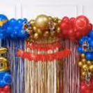 Close-up of balloon arch with chrome gold, dark blue, and red balloons, Wonder Woman cutouts.