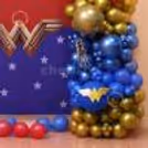 Dark blue frill curtain with blue balloon bunches and Wonder Woman paper cutout in decoration.
