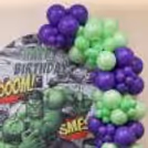 Superhero birthday decoration with organic balloon clusters next to a Hulk Character Foil Balloon.