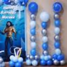 Alternating pastel, chrome and dark blue balloons arranged vertically to create a wave around the party area.