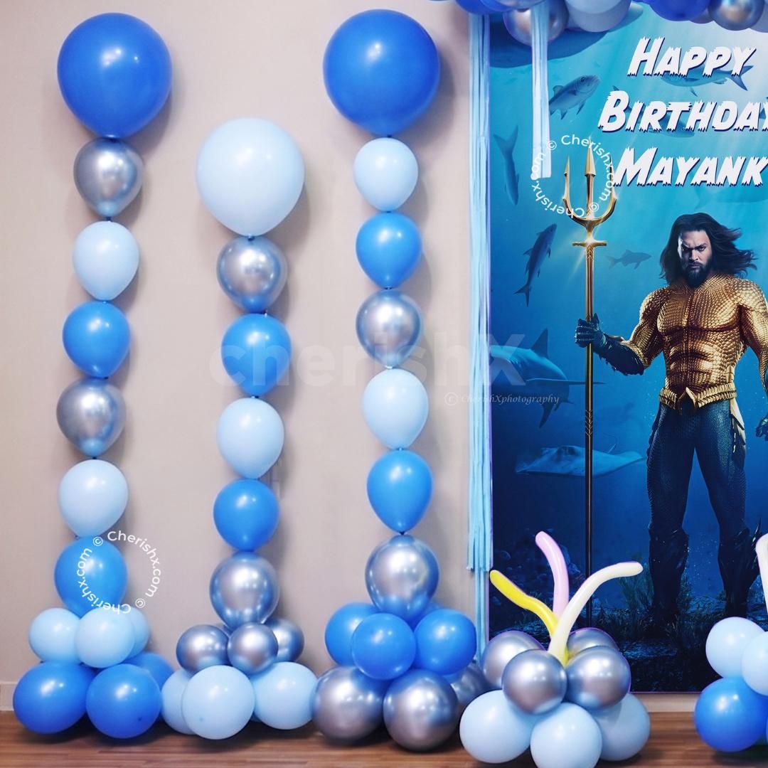 Superhero-themed party with a sea touch and themed character cutout and clusters of floor balloons.