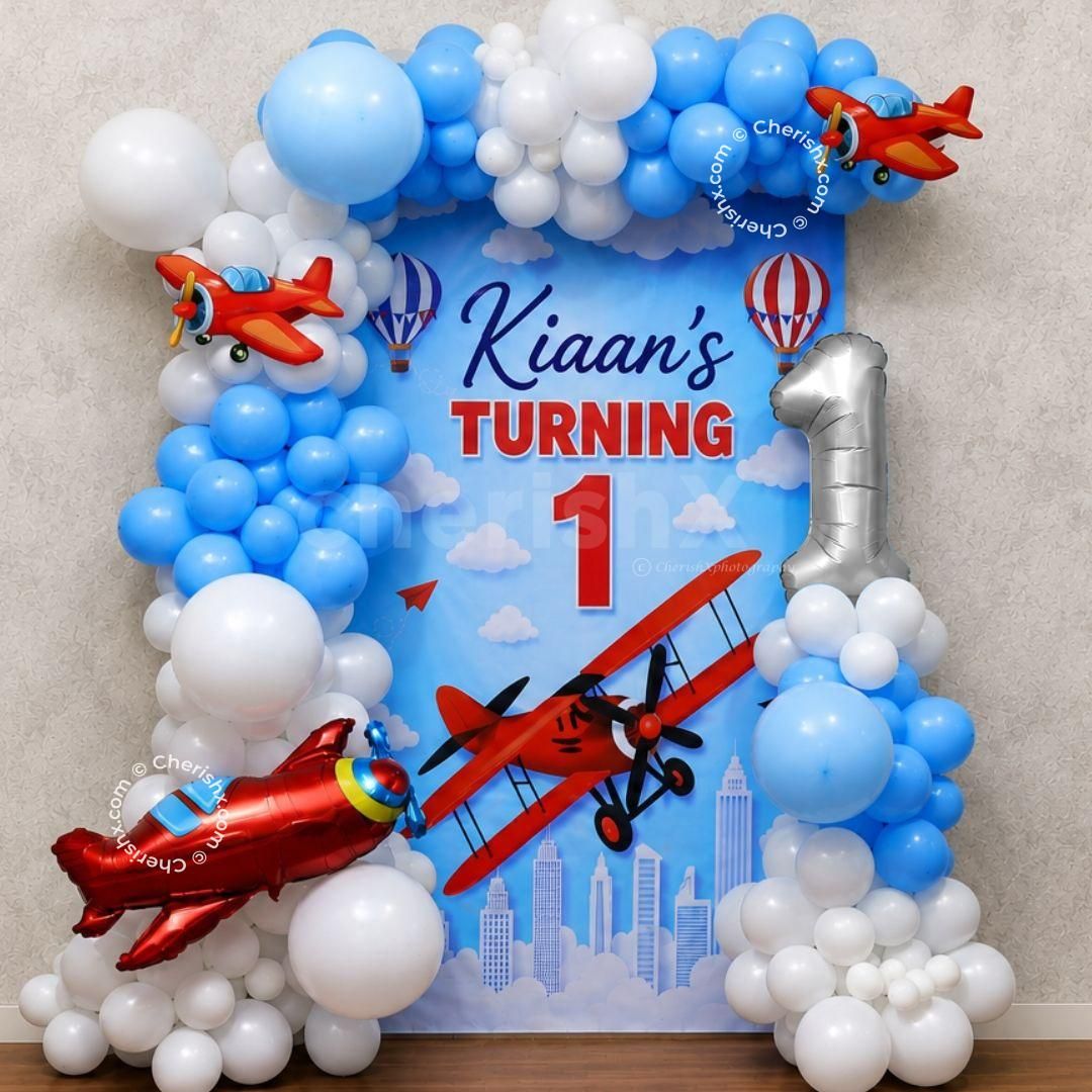 Airplane party background with custom name board, balloon arch and 1st birthday decoration.