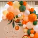 Botanical baby shower decorations with leafy and fruit details and a modern pastel backdrop.