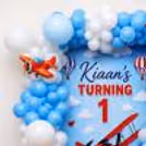 Airplane party background with custom name board, balloon arch and 1st birthday decoration.