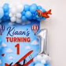 Bright airplane prop, soft balloon decors and personalized sky-themed birthday wall.