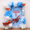 Red airplane balloon next to white balloon clusters, a themed birthday decoration display.