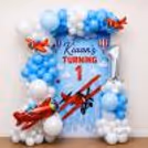 Red airplane balloon next to white balloon clusters, a themed birthday decoration display.