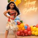 Close-up of Moana-themed birthday party with pastel balloons, tropical flowers and green monstera leaves.