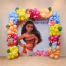Birthday display themed on Moana, featuring a large customised backdrop, coloured balloon framing, tropical foliage and character theme centrepiece.