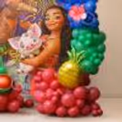 Close-up of tropical party details including foil balloons shaped like pineapples and watermelons, colourful latex balloon displays and a Moana character display.