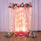 Lovely Ganesh festival wall decoration with strings of white jasmine, tassels made of pink net, high-quality ring hangings and warm, soft lighting.