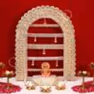 White platform with Ganesh idol, lotus lamps and rose petals.
