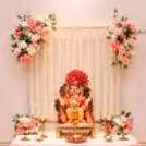 Ganpati idols with white jasmine strings on a golden background with pastel pink flowers