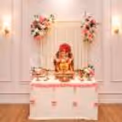 Ganpati idol decorated with a floral backdrop and traditional diyas