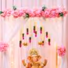 Close-up of fake pink flowers and lotus decoration in the Ganpati setup.