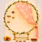 A peach draped with warm fairy lights, surrounded by green leaves and yellow blossoms.