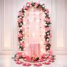 Elegant pink floral arch with warm lights and a draped table for Ganpati decoration.