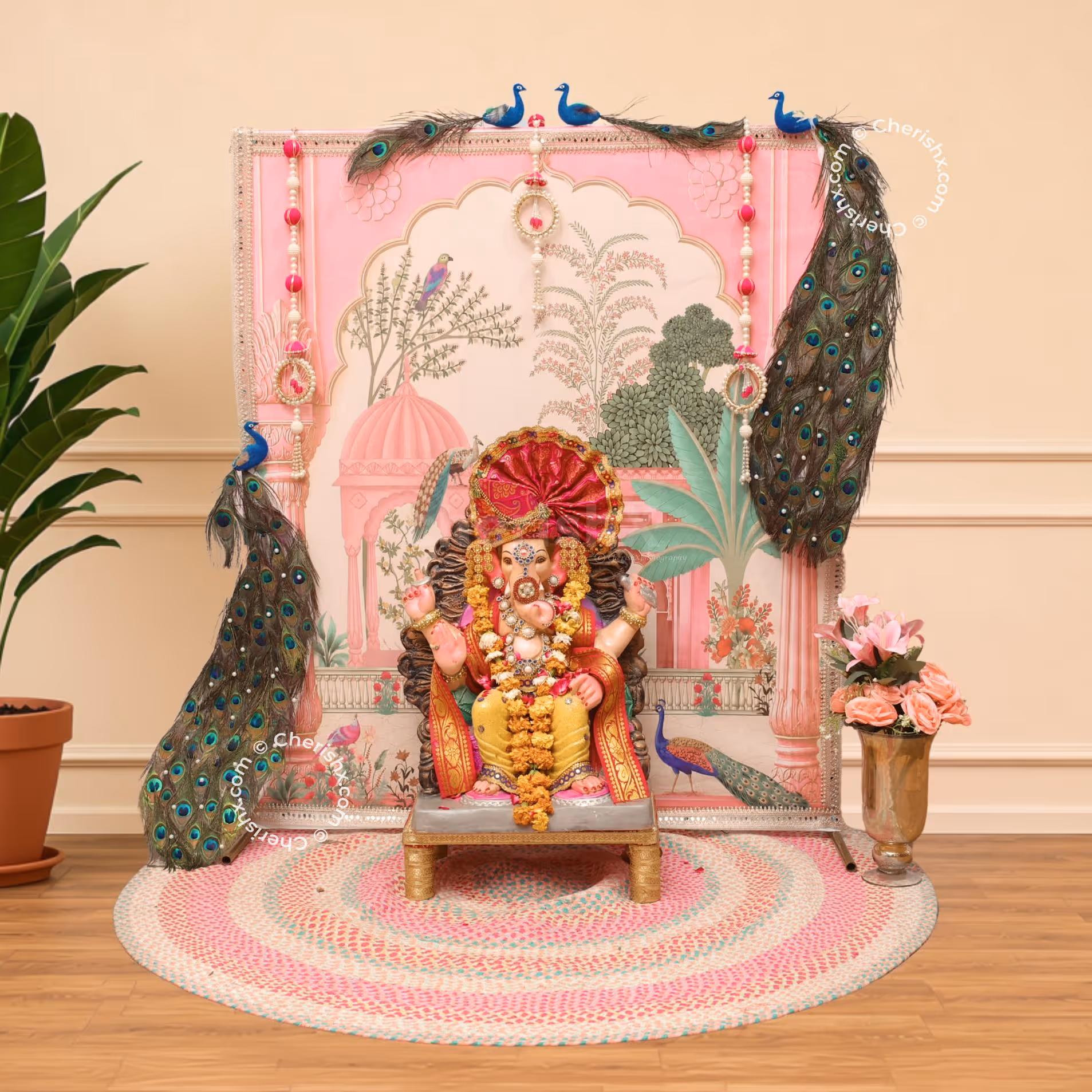 Royal peacock theme with Ganpati backdrop, complex pink and gold design and floor arrangement.