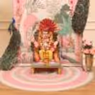 Close-up of detailed Ganpati pandal with peacock feathers, pearl decoration and pink embellishment.