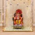 A Ganpati idol against a glittery gold background with hanging mirror balls.