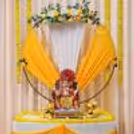 Ganpati celebration setup with yellow and white draped fabric background and a golden ring in the middle.