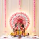 Floral Ganpati backdrop with Artificial rose wall decoration, illuminated round frame, hanging garlands in pink and MDF lotus accents.