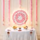 Pink and white circular artificial rose backdrop for Ganpati decoration with glowing LED strip lights and layered flowers.