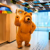 Live bear mascot waving with a friendly smile in a children's birthday party entertainment session.