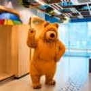Live bear mascot waving with a friendly smile in a children's birthday party entertainment session.