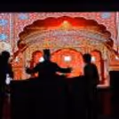 A magician performing at a grand illusion stage setting with LED backdrop and lighting effects.