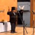 A celebration, with the public watching a magician performing a table levitation and illusion routine.