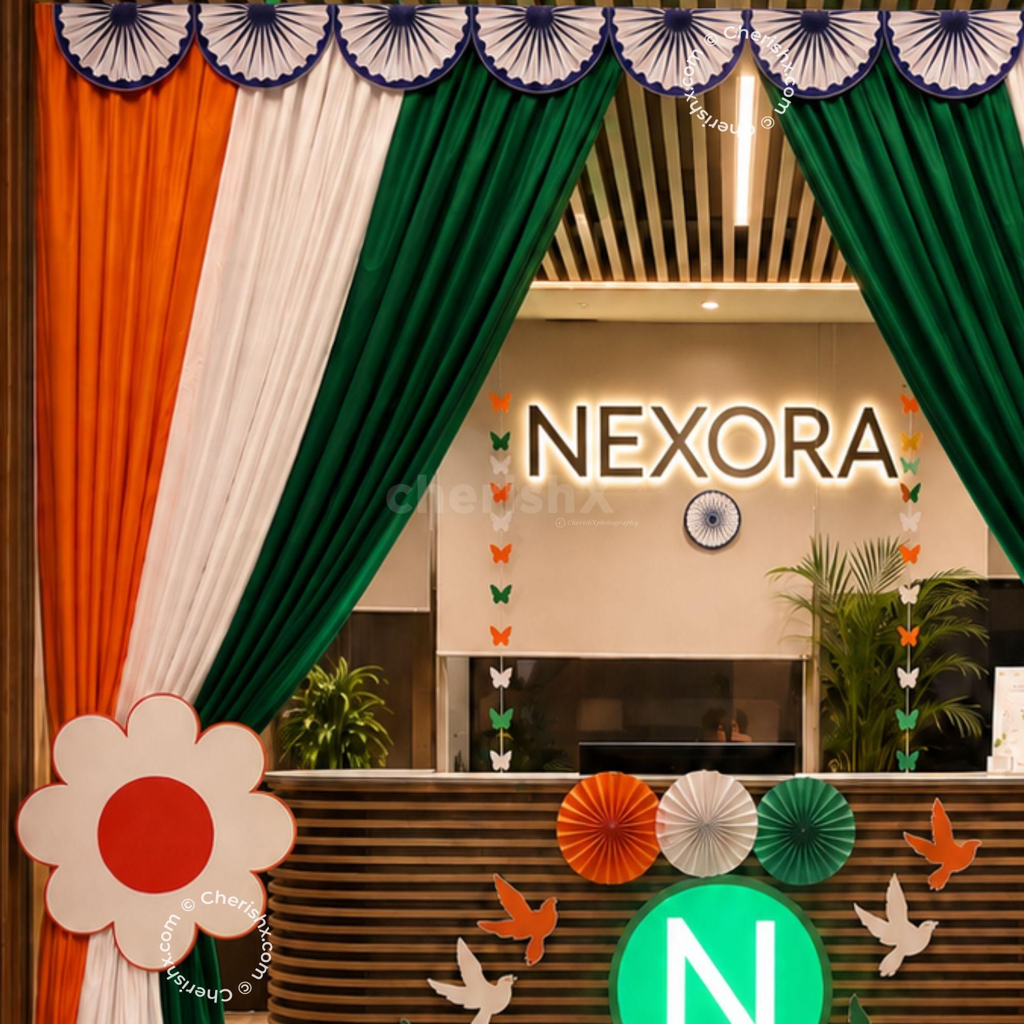 Patriotic hanging decorations, flower sunboards and satin drapes are some of the elegant Independence Day Tricolor Entrance Decoration options for office events.