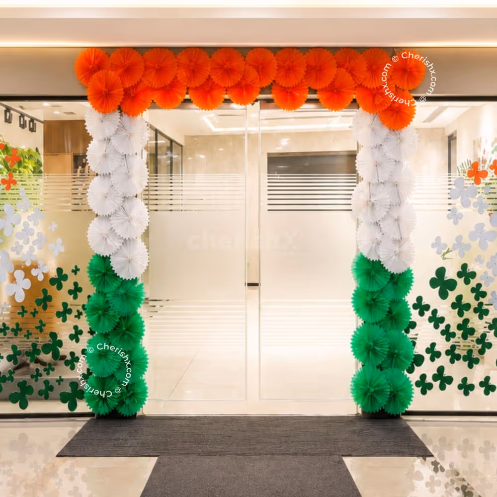 Orange, white, and green paper rosettes entrance wall decor for Independence Day entrance decoration.