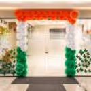 Orange, white, and green paper rosettes entrance wall decor for Independence Day entrance decoration.