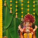 DIY Ganpati Backdrop with Banana Leaf and floral garlands with a Ganpati idol in a golden frame.