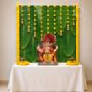 DIY Banana Leaf Ganpati Backdrop with green leaf design, yellow rose hangings, and decorative bells.