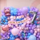 Pastel balloon backdrop for birthday, with Stitch and Angel character decor and Happy Birthday banner.