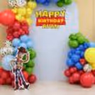 Close-up of Toy Story birthday decorations including a Happy Birthday backdrop, Woody cutout, and multi-coloured balloon arrangement.