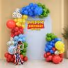 Toy Story theme birthday party decoration, colourful balloon arch, blue theme backdrop and Woody character cutout.