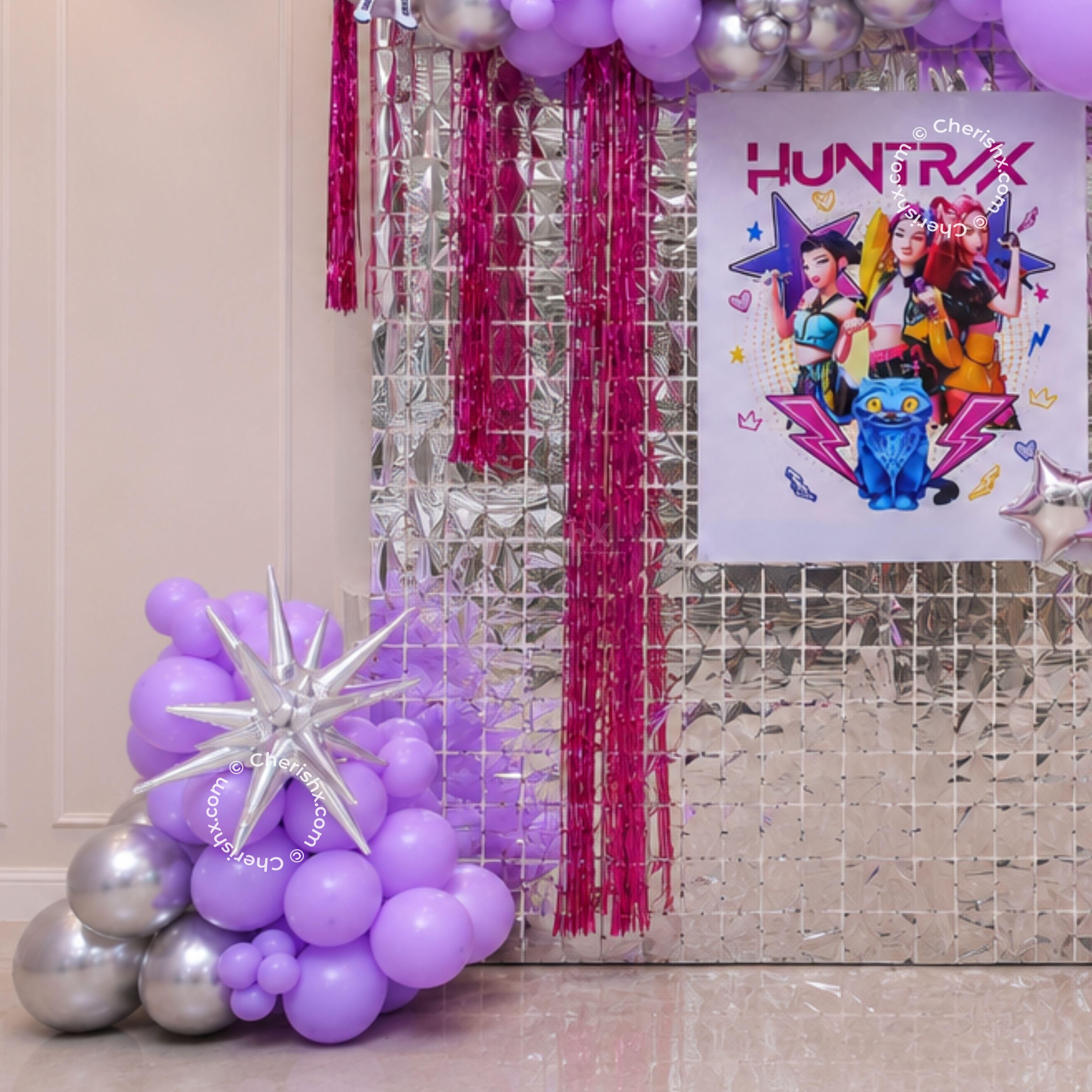Purple starburst balloon clusters on either side of the backdrop for the birthday.