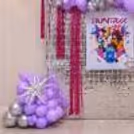 Purple starburst balloon clusters on either side of the backdrop for the birthday.
