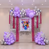 Pink foil fringe curtains and Huntrix character cutouts complete the K-pop party display.
