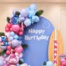 Balloon arch with Stitch character decorations in a pastel pink, blue, and purple color theme for a themed birthday party.