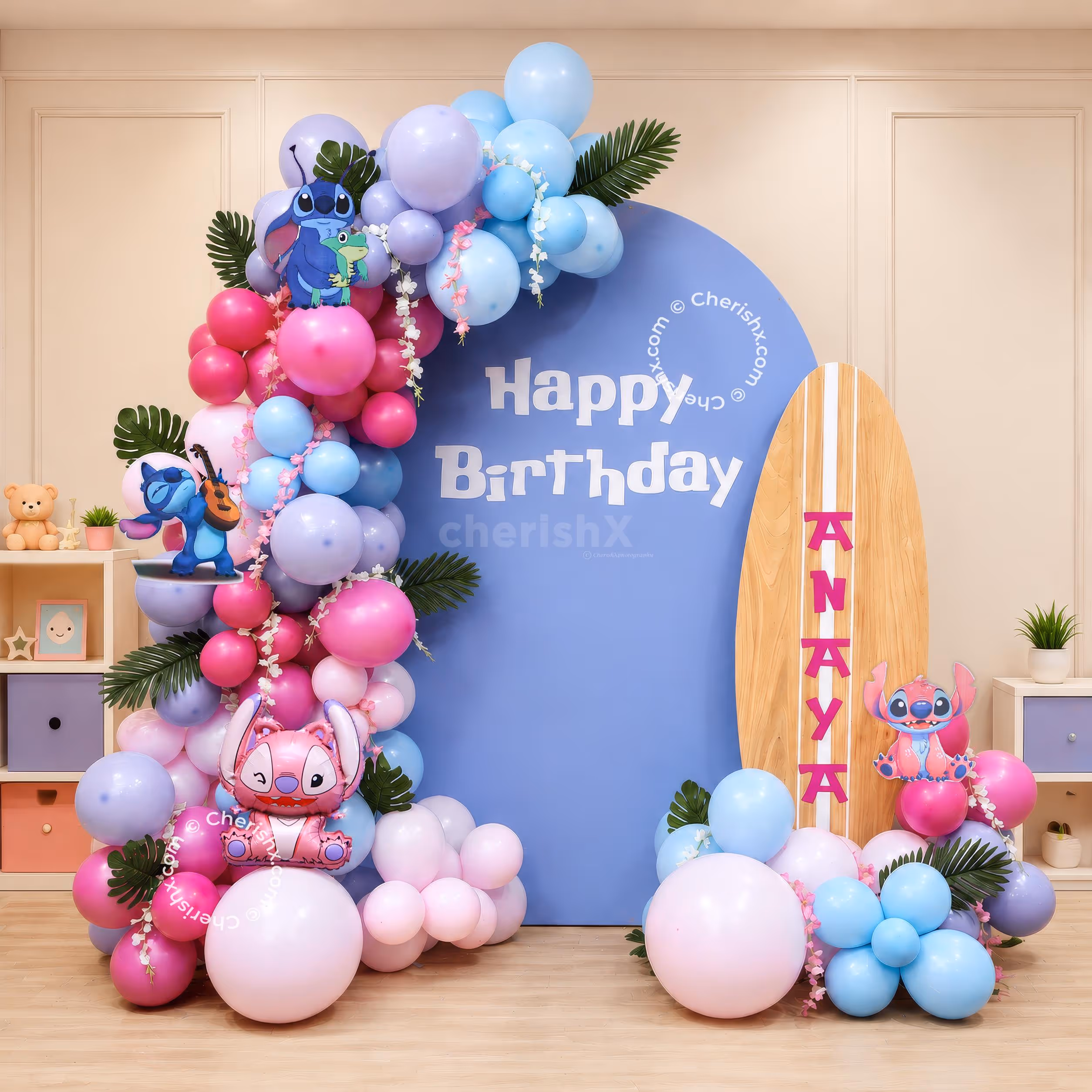 Stitch Surf Adventure birthday decoration with pastel balloon arch, blue backdrop and large surfboard cutout.