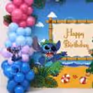 Birthday scene with character decorations and blue and pink balloon arrangement, tropical Stitch.
