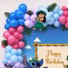 Stitch birthday wall decor with colourful balloons, leafy accents and cartoon cutouts.